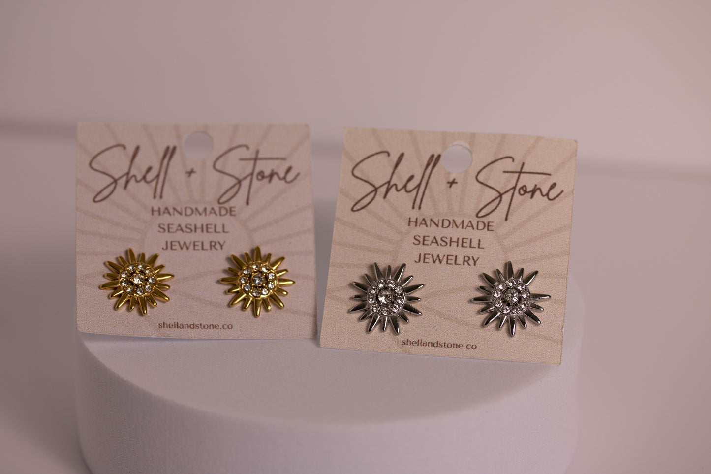 Two pairs of shell earrings on 'Shell & Stone' branded cards against a light background.