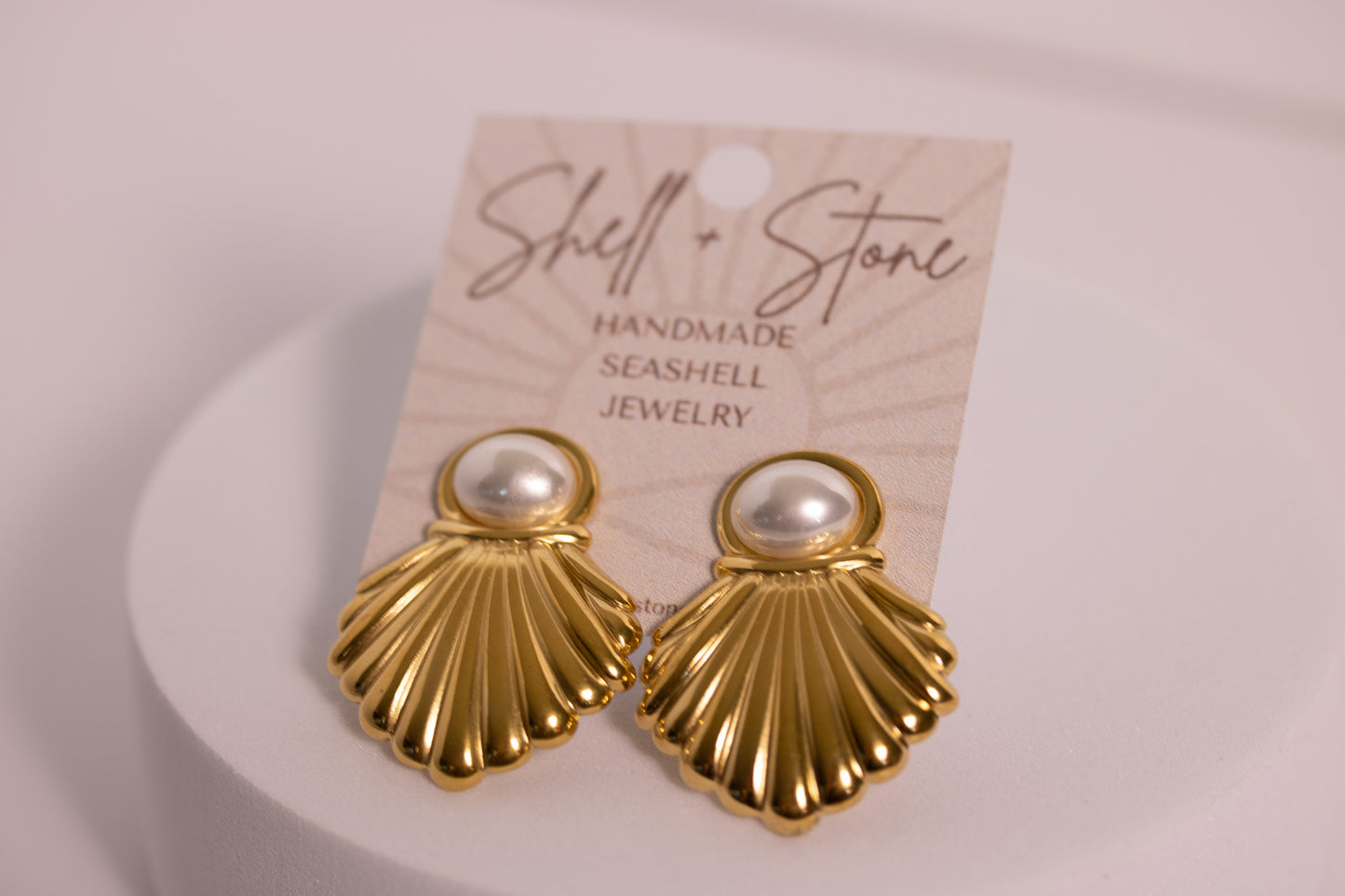 Gold shell earrings with pearl centers on a 'Shell & Stone' branded card.