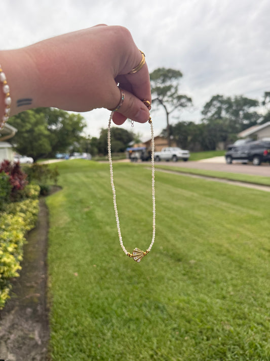 Hand holding a necklace with a blurred outdoor background